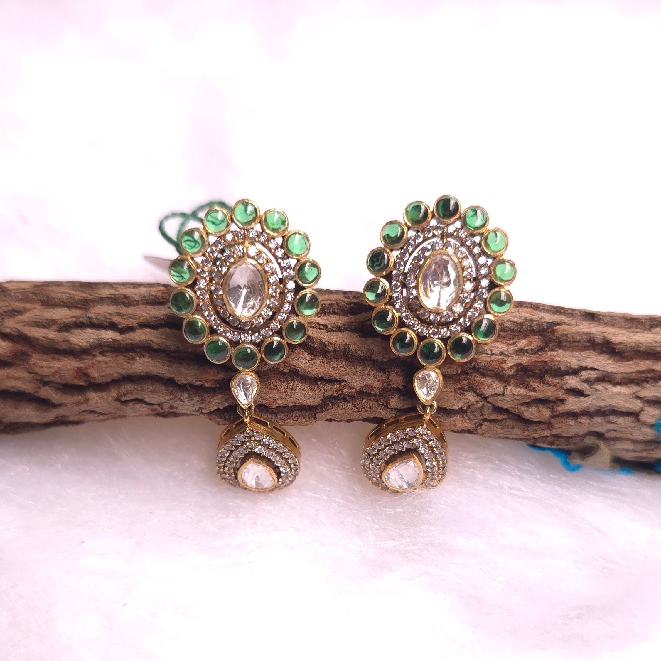 Emerald Drop Earrings featuring intricate gold detailing and green embellishments on a wooden background.