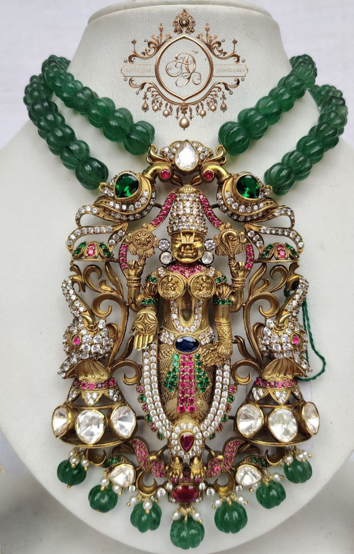 Divine Lord Venkateswara pendant with intricate design and gemstones on a jewelry display.